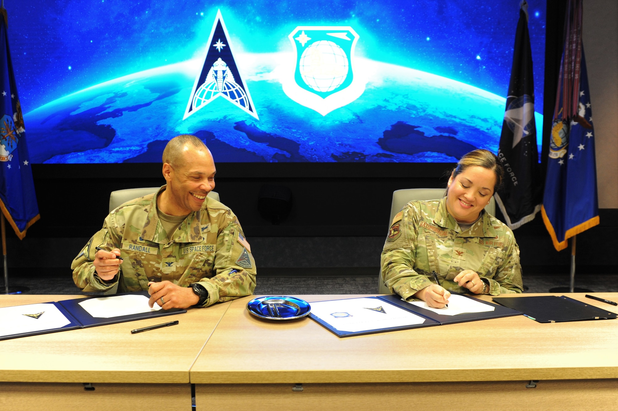 Col. Marqus D. Randall, National Space Intelligence Center commander, and Col. Ariel G. Batungbacal, National Air and Space Intelligence commander, share a laugh as they sign a Memorandum of Agreement at Wright-Patterson Air Force Base, Ohio, Feb. 10, 2023. During the MOA signing ceremony, the two commanders pledged continued integration and teamwork between the two Centers as they work together to make foundational discoveries that help keep the nation safe.