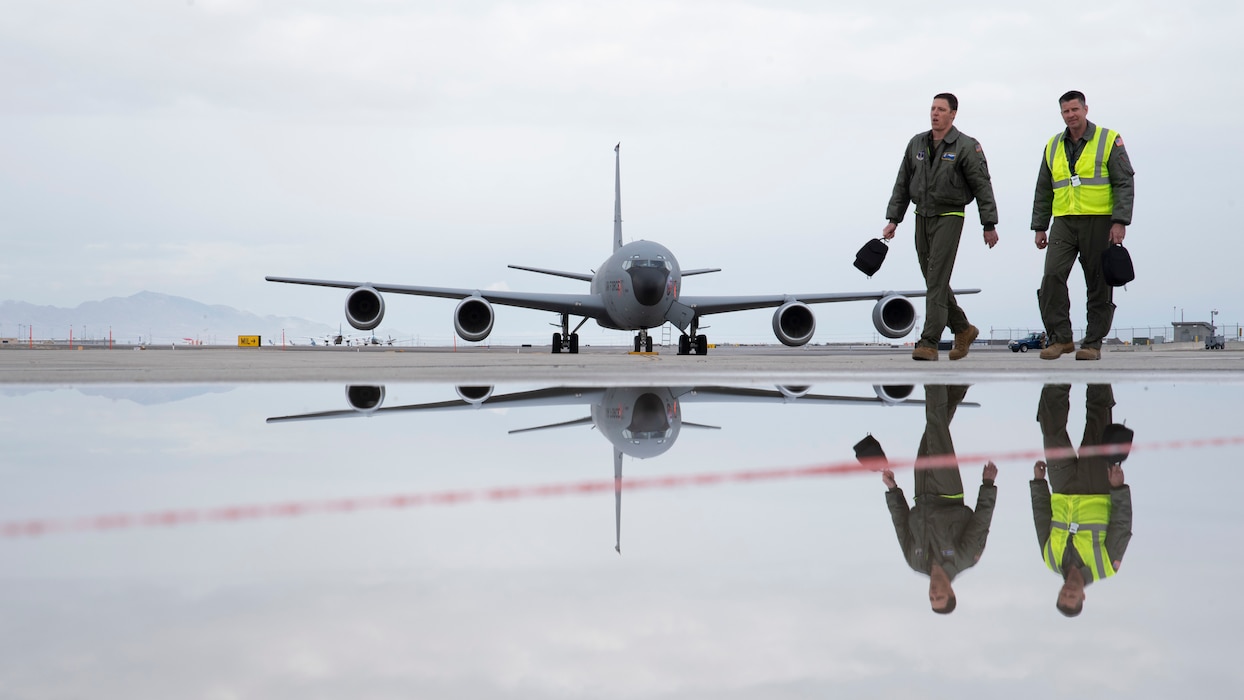 Two Air Force pilots walk across flightline in front of KC-135R