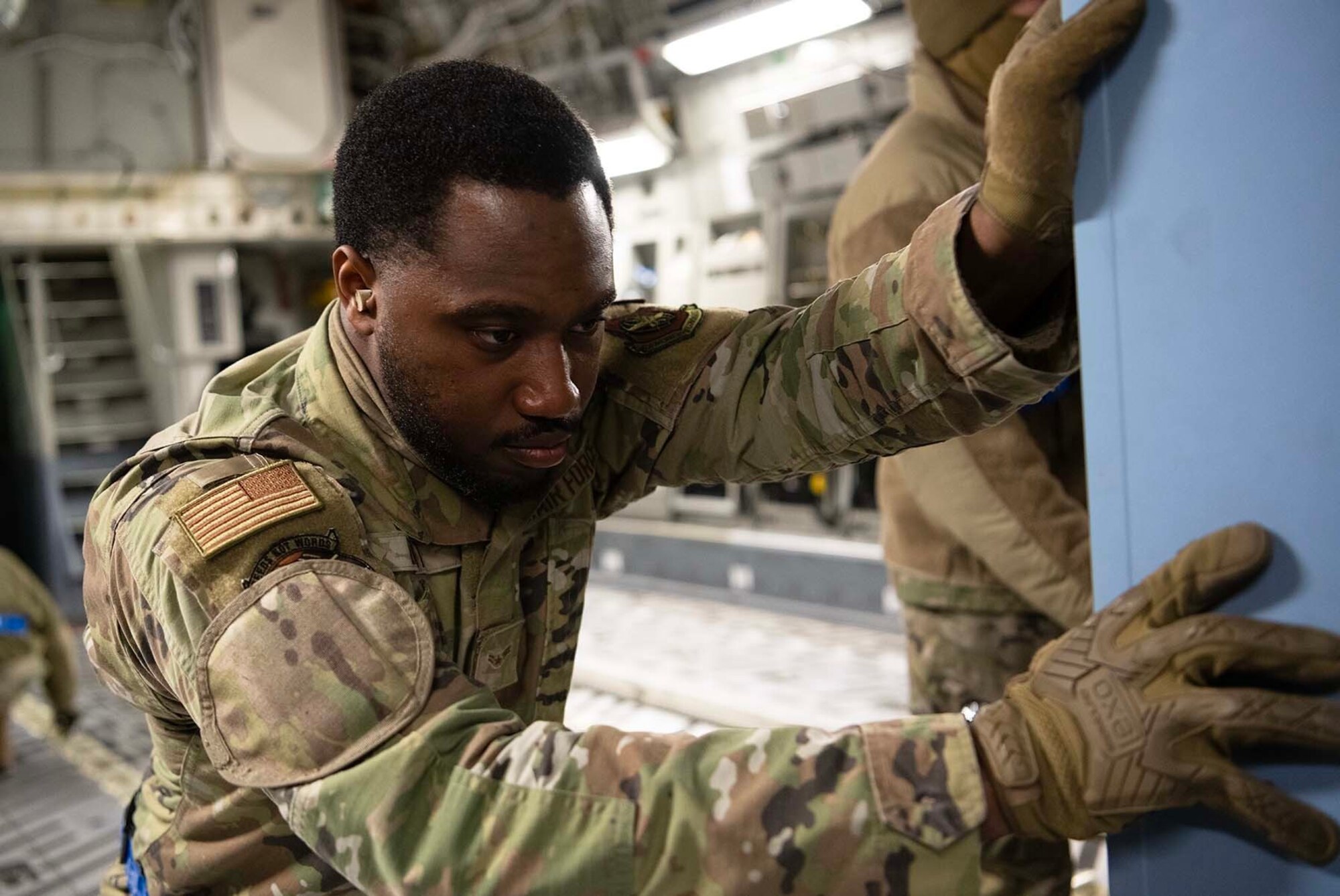 An Airman pushes cargo inside of a plane