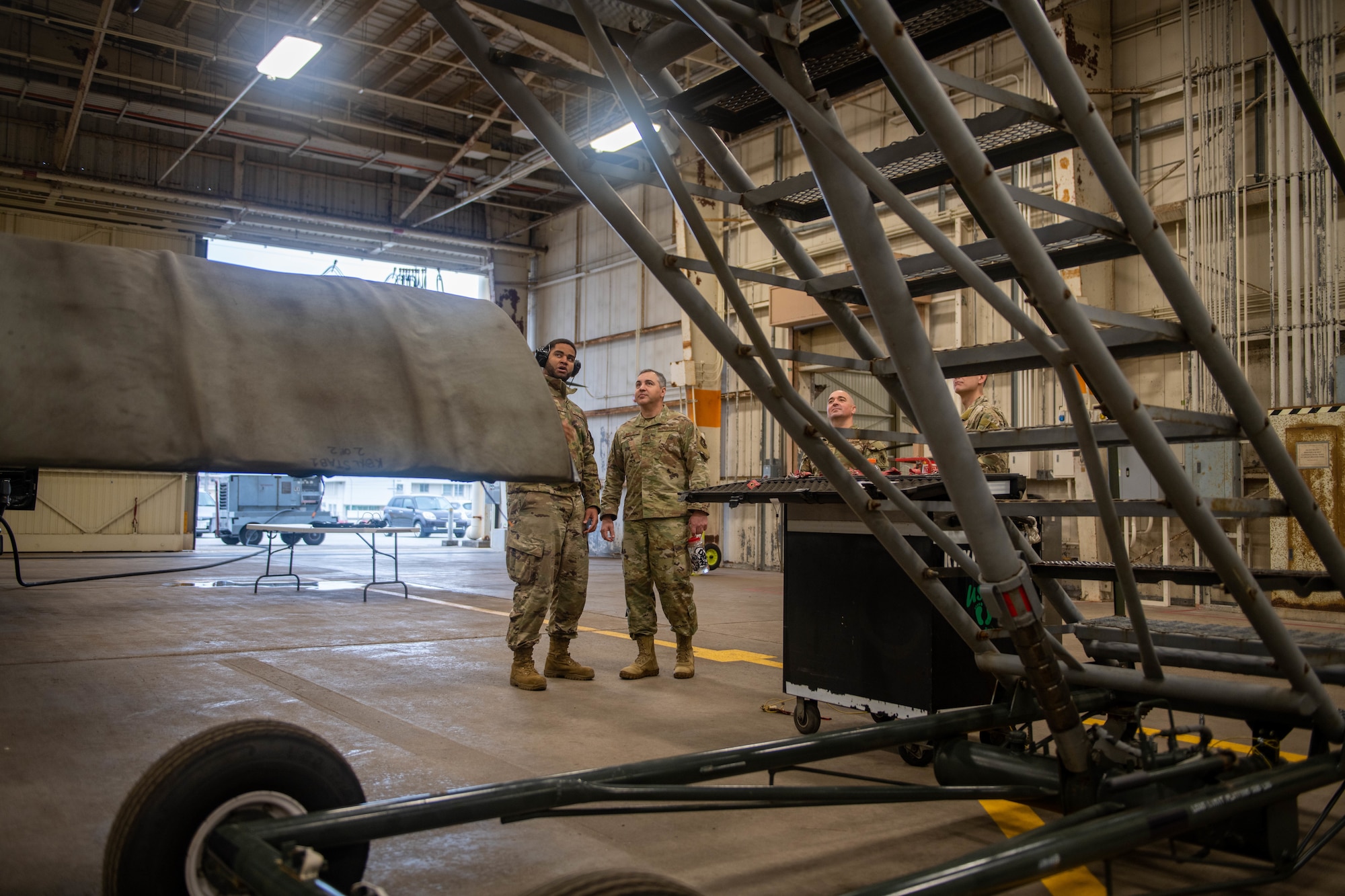 A group of Airmen stand beside a helicopter under maintenance.