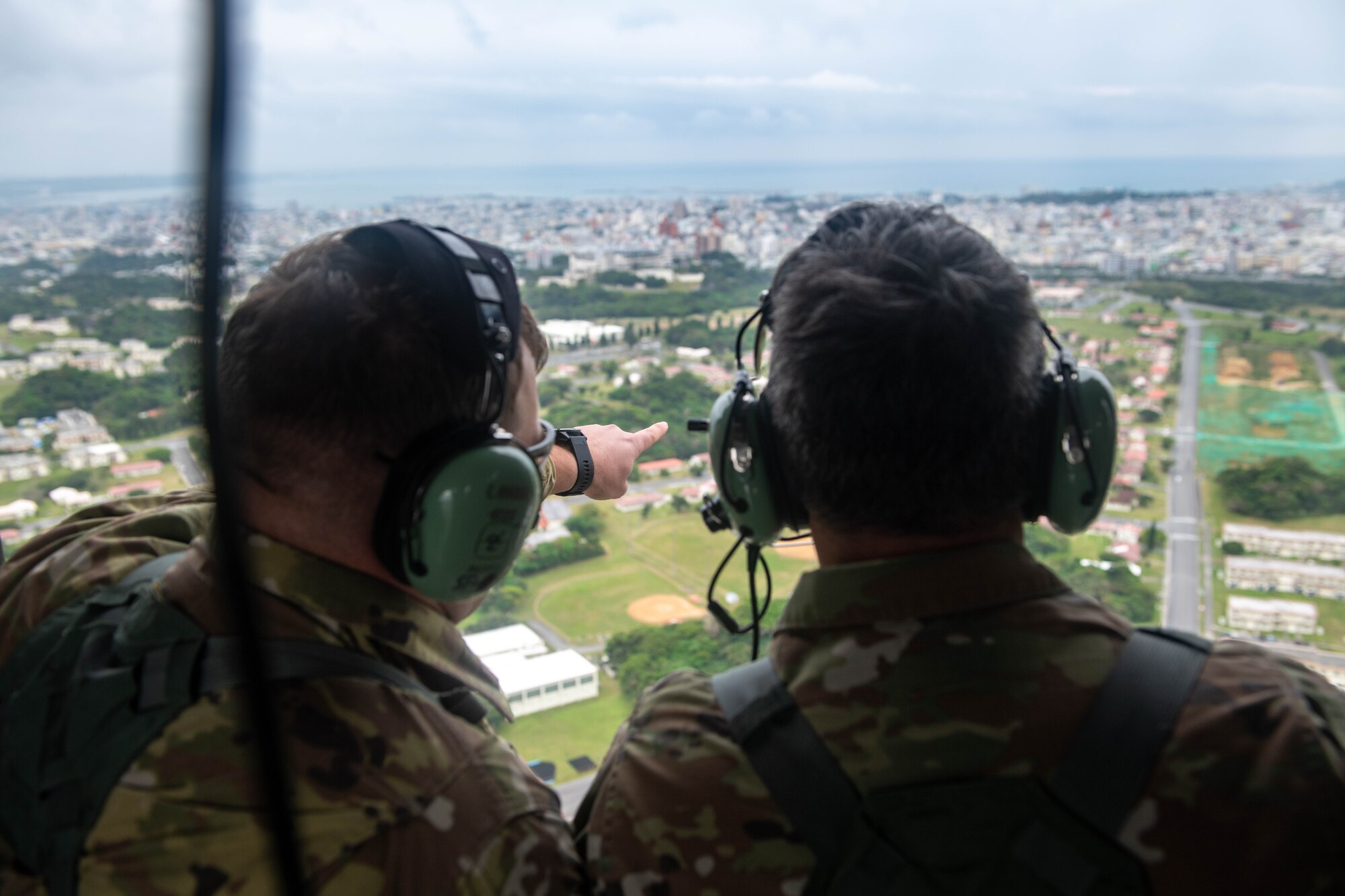 Two Airmen point into the distance on a helicopter.