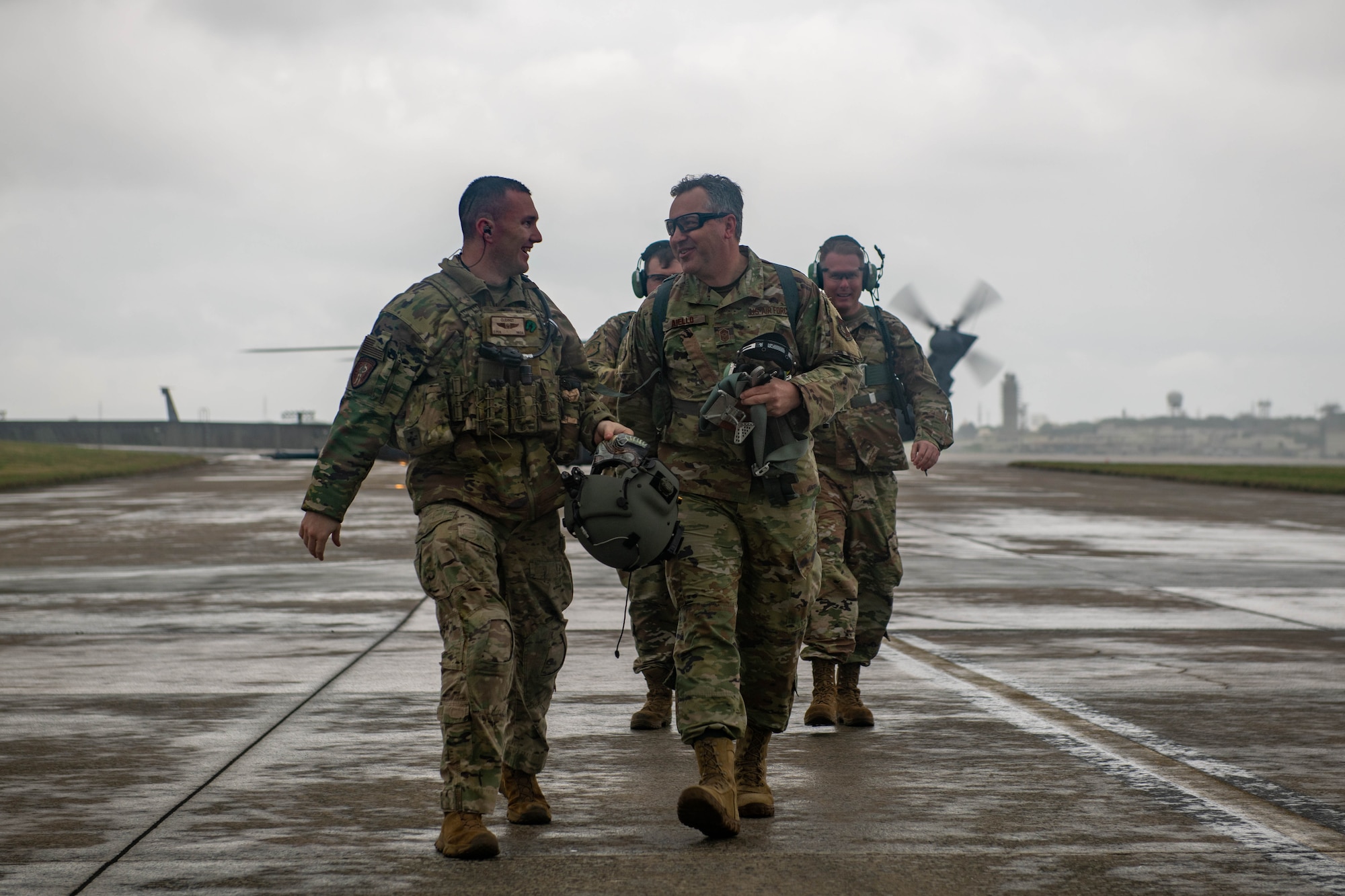 A CMSgt walks away from a helicopter with a group of Airmen.