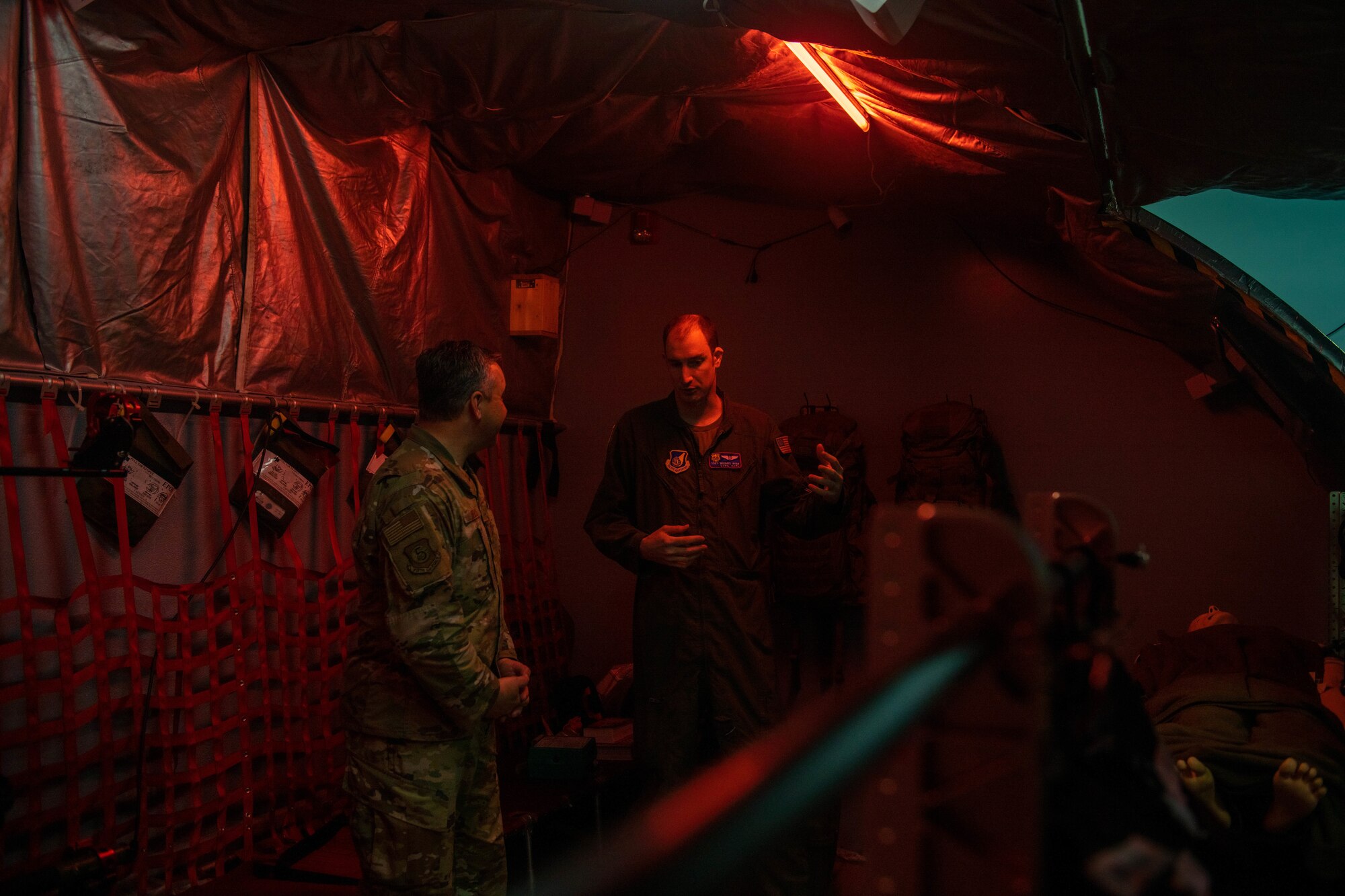 Two Airmen stand in a modeled aircraft.