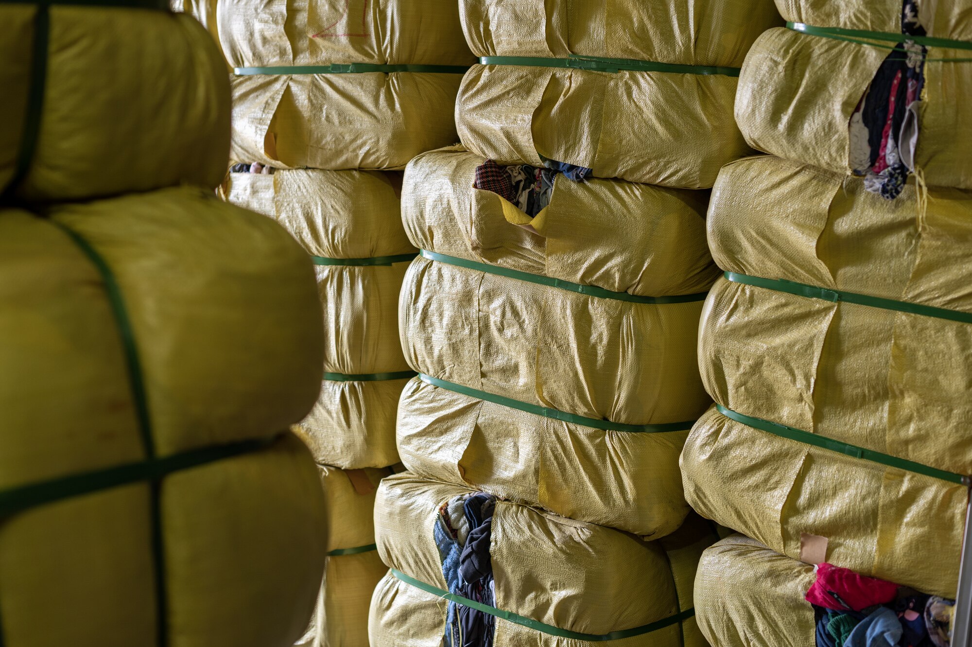 Bundles of clothes are packaged in yellow plastic and stacked on top of each other.