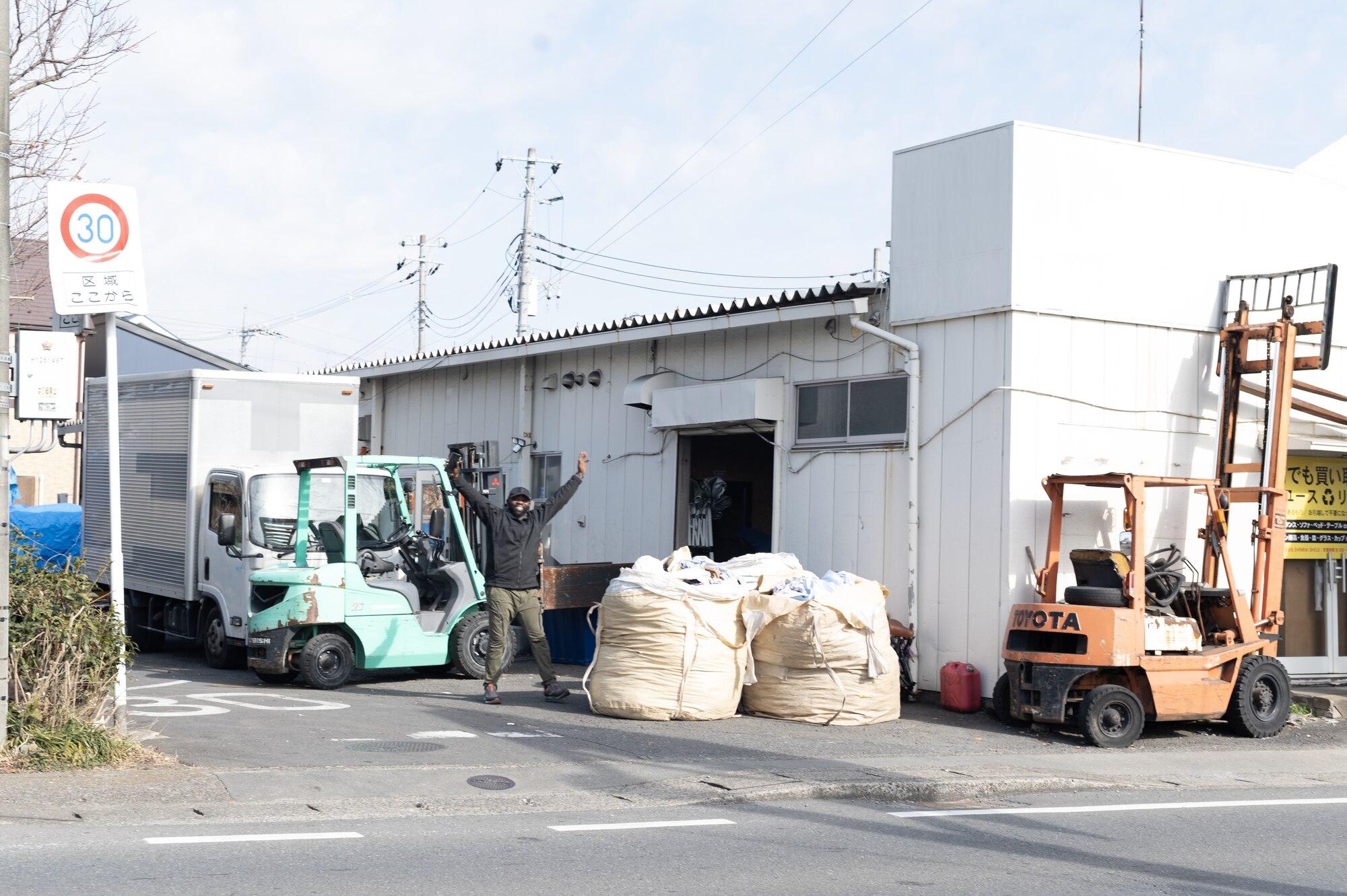 A black man stands in front of a warehouse.