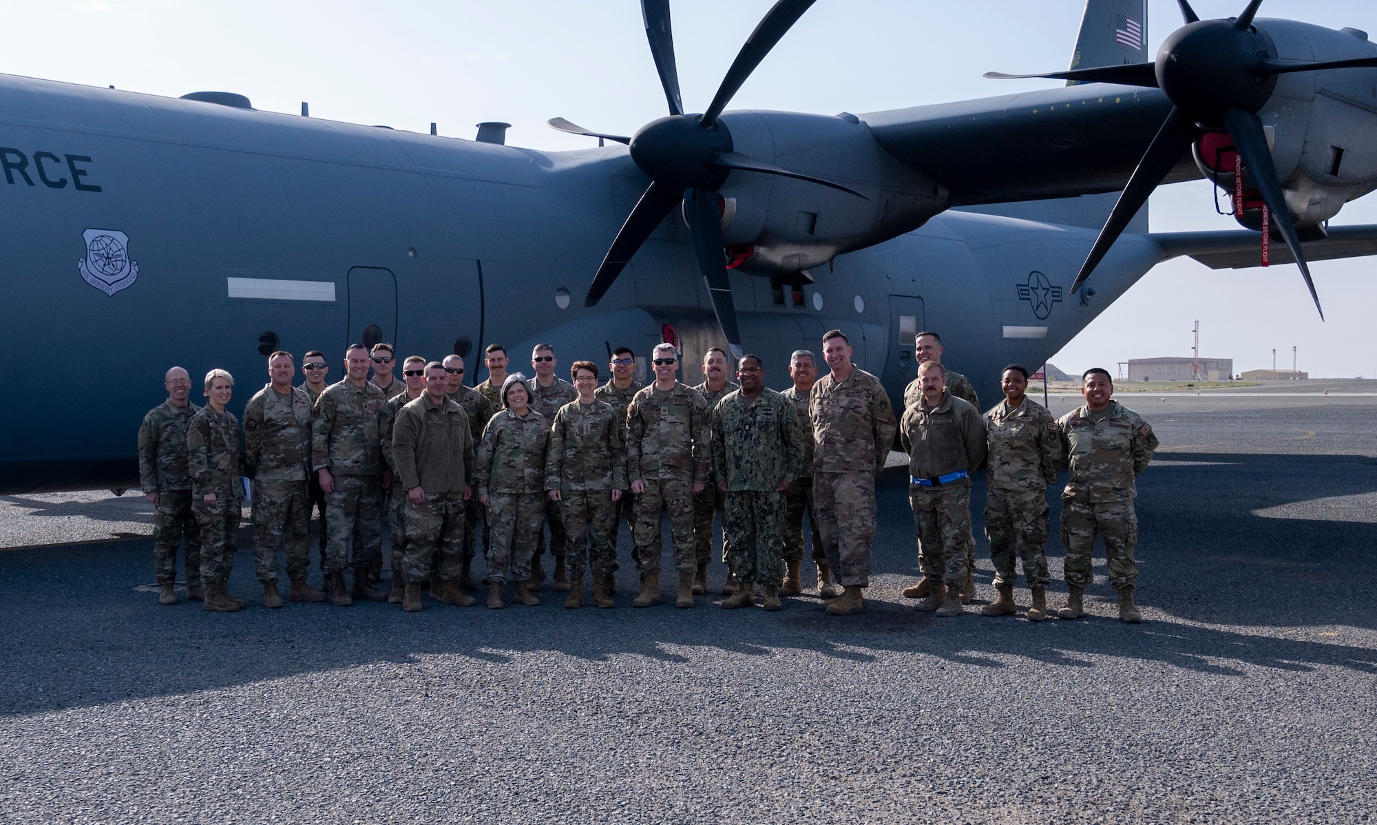 U.S. Air Force Gen. Jacqueline Van Ovost, U.S. Transportation Command commander, and U.S. Navy Fleet Master Chief Petty Officer Donald O. Myrick, U.S. Transportation Command senior enlisted leader, pose for a photo with Airmen from the 386th Expeditionary Aircraft Maintenance Squadron by a C-130J Super Hercules at Ali Al Salem Air Base, Kuwait, Feb. 10, 2023.