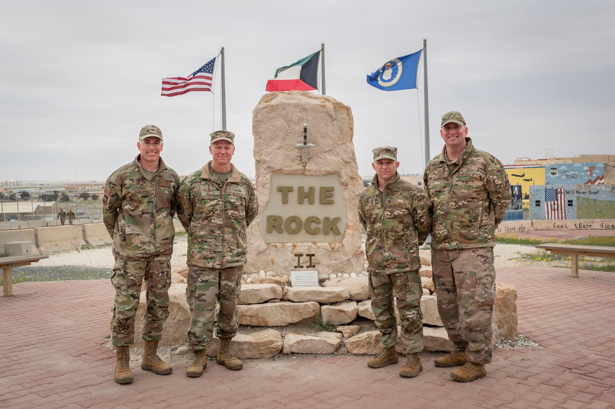 From left, U.S. Air Force Col. George Buch, 386th Air Expeditionary Wing commander, Gen. Mark Kelly, commander of Air Combat Command, Command Chief Master Sgt. John Storms, Air Combat Command, and Chief Master Sgt. Louis Ludwig, 386th AEW command chief, pose for a photo in front of “The Rock” during a tour at Ali Al Salem Air Base, Kuwait, Feb. 15, 2023.