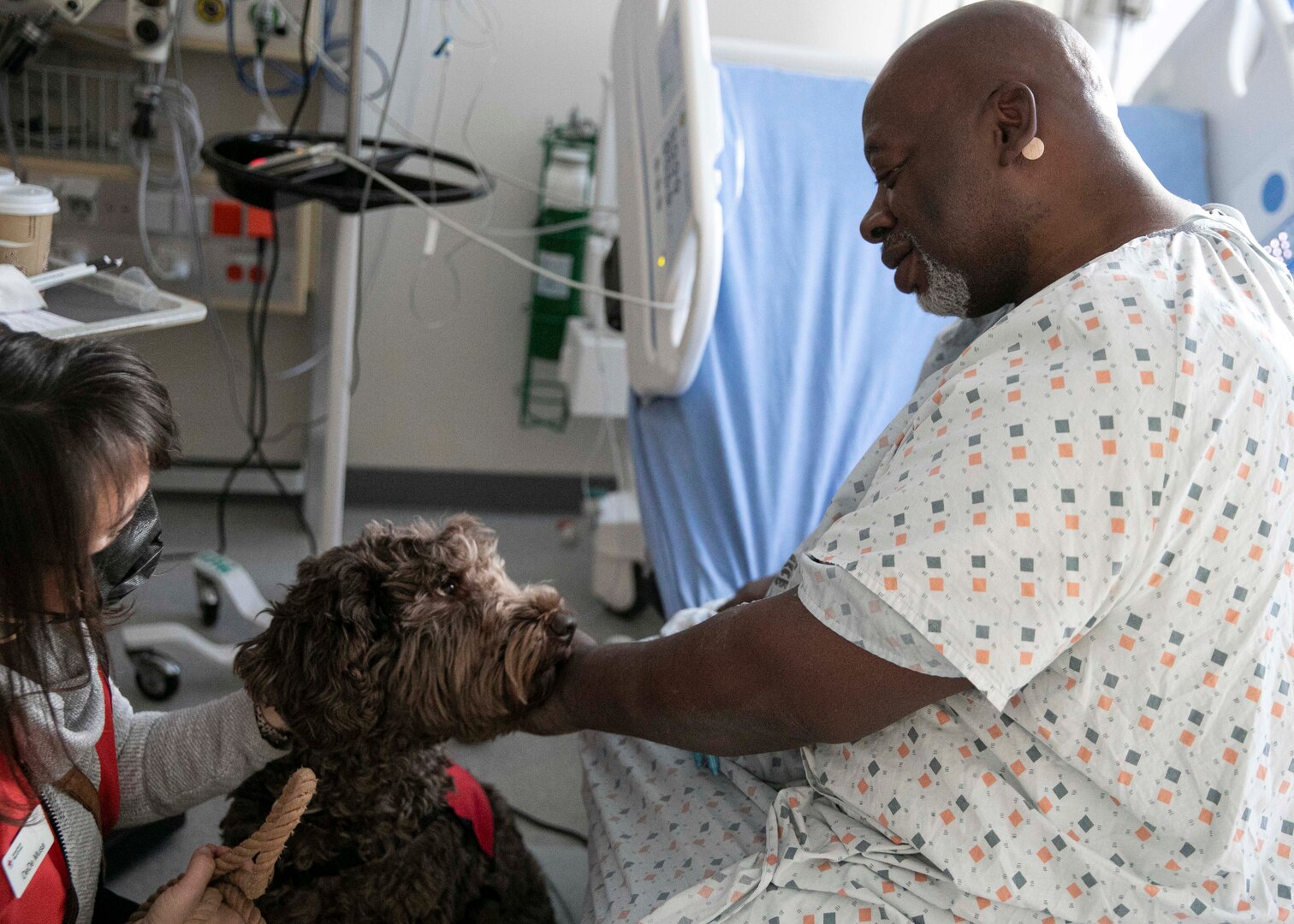 Nathan Yancy, a local retiree and inpatient at Landstuhl Regional Medical Center's Medical Surgical Ward, pets Saif, an American Red Cross volunteer, during Saif’s first day volunteering with the Landstuhl American Red Cross Pet Visitation Program, at Landstuhl Regional Medical Center, Jan. 19.