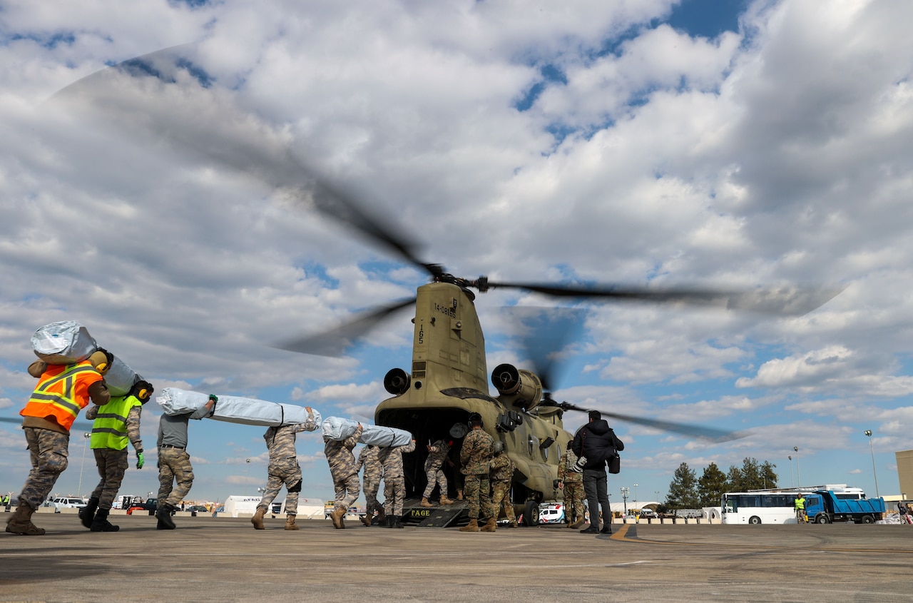 A group of U.S. Marines, soldiers and Turkish airmen load humanitarian aid onto a CH-47 Chinook helicopter.