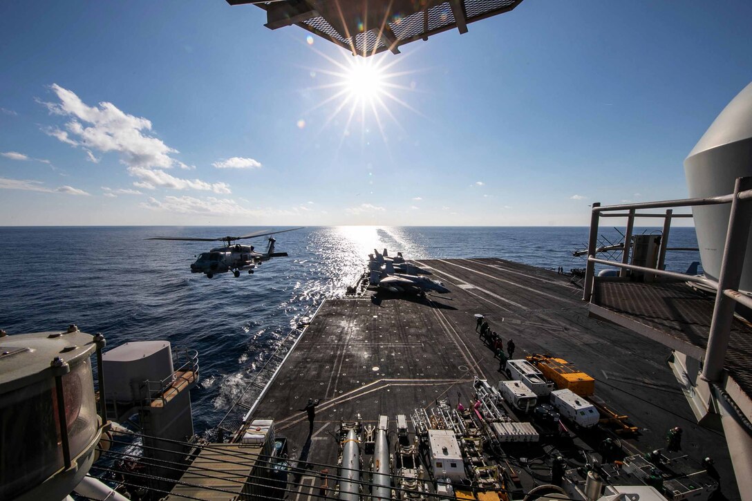 A helicopter takes off from an aircraft carrier at sea.