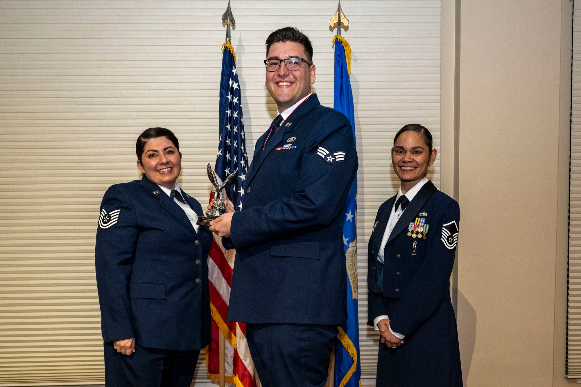 Senior Airman Brennan Wannamacher, 4th Operations Support Squadron airfield management operations supervisor, center, receives a distinguished graduate award from Tech. Sgt. Christine Intorre, 4th Component Maintenance Squadron electrical and environmental section chief, left, and Master Sgt. Sherri Santos-Orton, 334th Fighter Generation Squadron weapons section chief, during Airman Leadership School Class 23-B graduation ceremony at Seymour Johnson Air Force Base, North Carolina, Feb. 9, 2023. Students who received the distinguished graduate award displayed effective teamwork, academic excellence and spirited leadership.