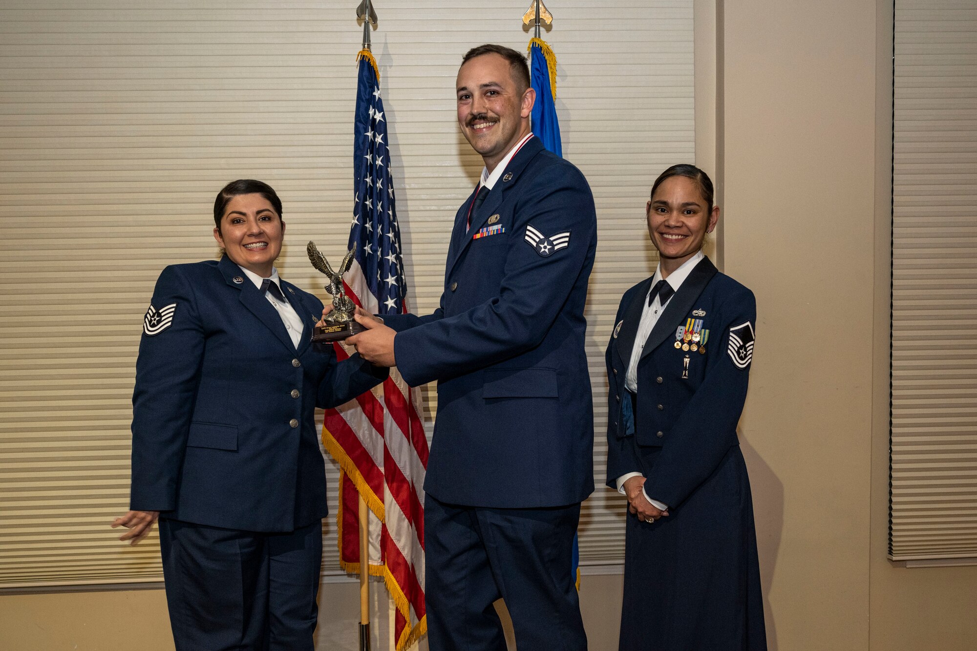 Senior Airman Joshua Strahin, 4th Operations Support Squadron airfield management operations supervisor, center, receives a distinguished graduate award from Tech. Sgt. Christine Intorre, 4th Component Maintenance Squadron electrical and environmental section chief, left, and Master Sgt. Sherri Santos-Orton, 334th Fighter Generation Squadron weapons section chief, during the Airman Leadership School Class 23-B graduation ceremony at Seymour Johnson Air Force Base, North Carolina, Feb. 9, 2023. Students who received the distinguished graduate award displayed effective teamwork, academic excellence and spirited leadership.