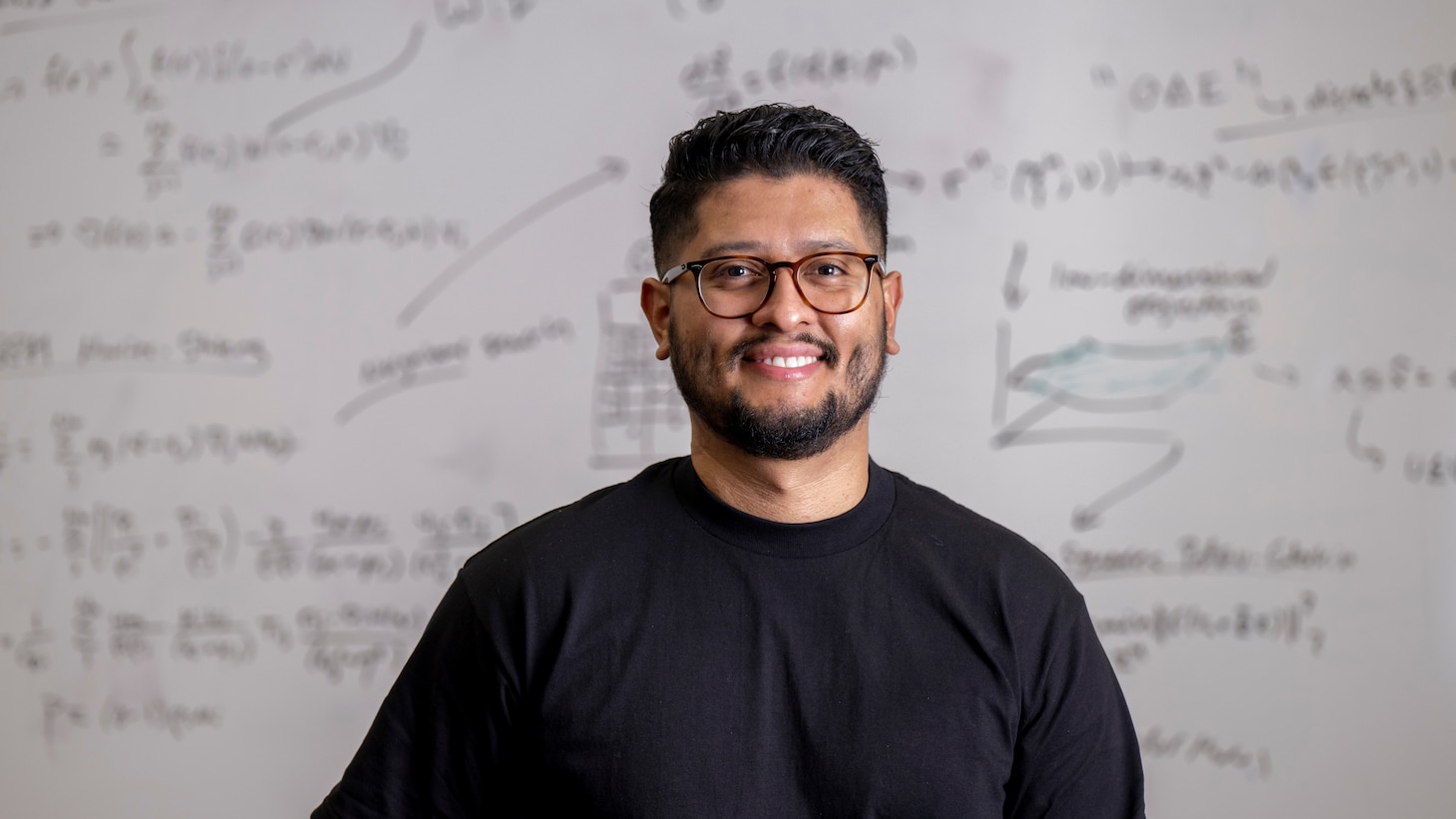 Steven Rodriquez, U.S. Naval Research Laboratory engineer in computational multiphysics and mathematics, stands in front of a model-order reduction approach for the delta-SPH formulation of the Navier-Stokes equations in Washington, D.C., January 20, 2023. Rodriquez was selected for Mathematically Gifted & Black – Society for Industrial and Applied Mathematics (MGB-SIAM) Fellowship in 2023.  (U.S. Navy photo by Jonathan Steffen)