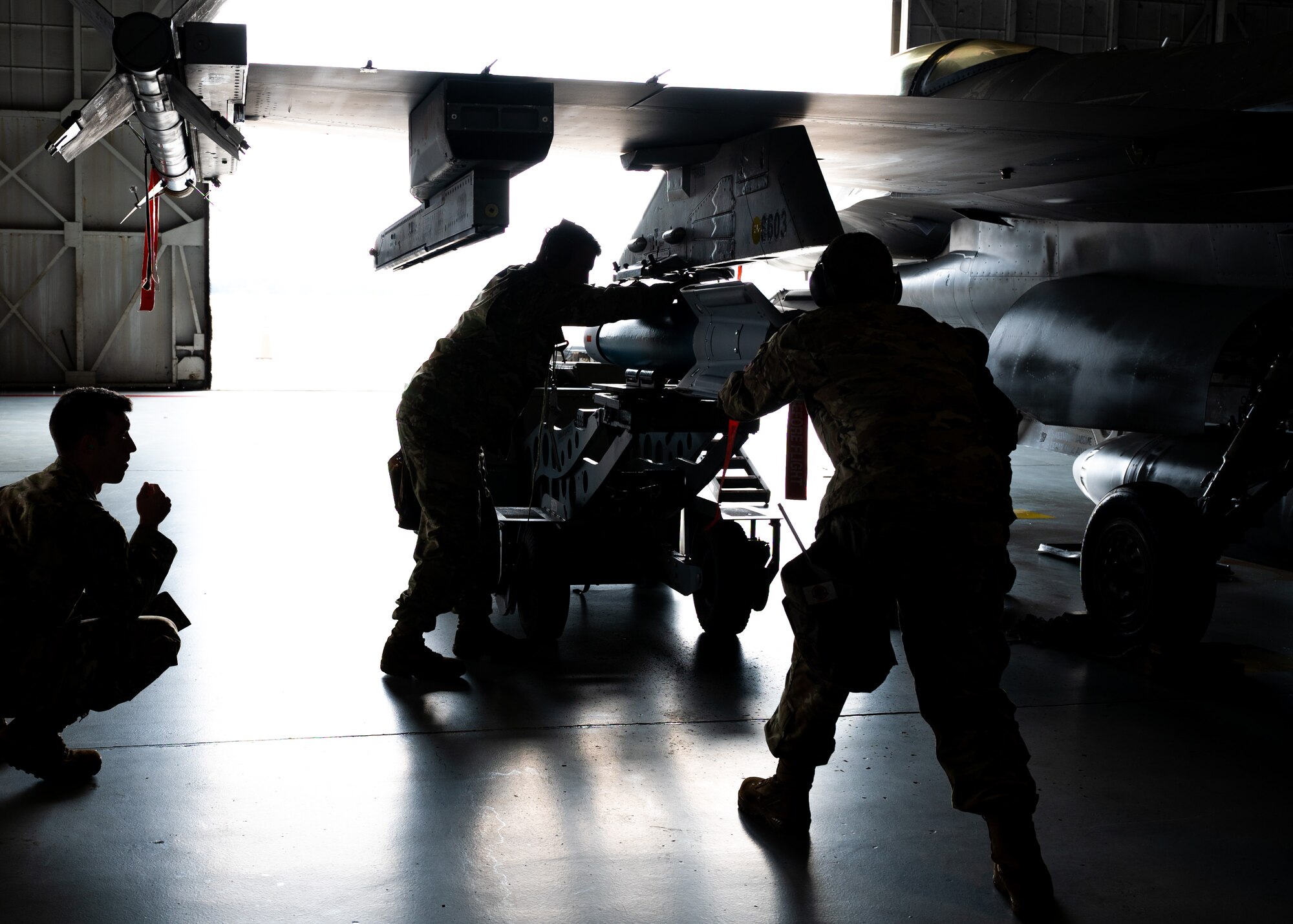 U.S. Air Force Airmen secure a munition to an F-16C Fighting Falcon