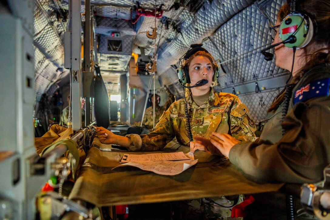 An airman speaks to an Australian service member inside an aircraft.