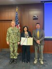 The Arleigh Burke Class (DDG 51) Destroyer Shipbuilding Program Manager Capt. Seth Miller (left) and Naval Sea Systems Flight (FLT) III Upgrade Manager PMS 400D Michael Dugan (right) present the Navy Meritorious Civilian Service Award to Toni Checchio, a Naval Surface Warfare Center, Philadelphia Division electrical engineer, for her performance throughout her 39-year career on Jan. 18, 2022 in Philadelphia. Checchio began working at NSWCPD in 1983 as a co-op, and she is set to retire on Feb. 28, 2023.