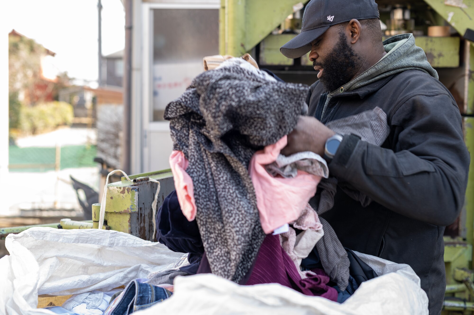 A black man takes some clothes out of a bag.