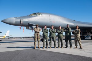 A photo of five people standing in front of a jet.