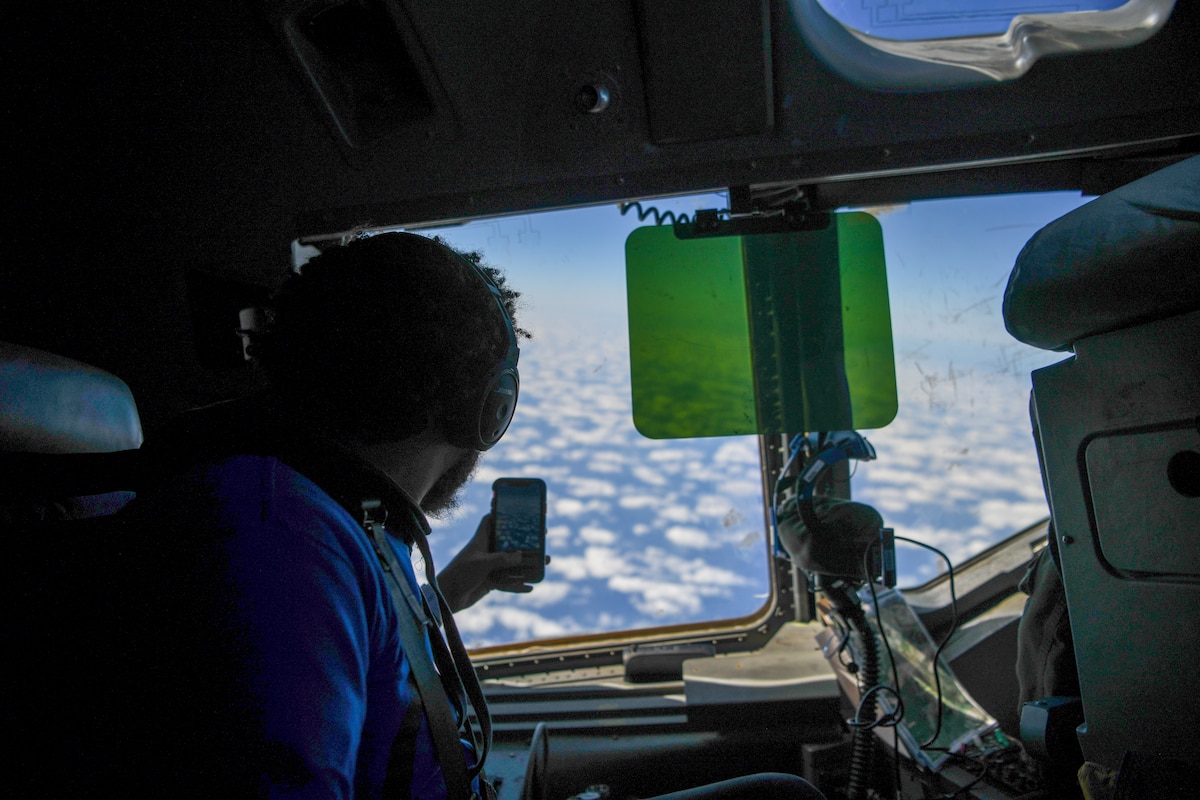 A photo of a student taking a photo out the window of a jet while flying.