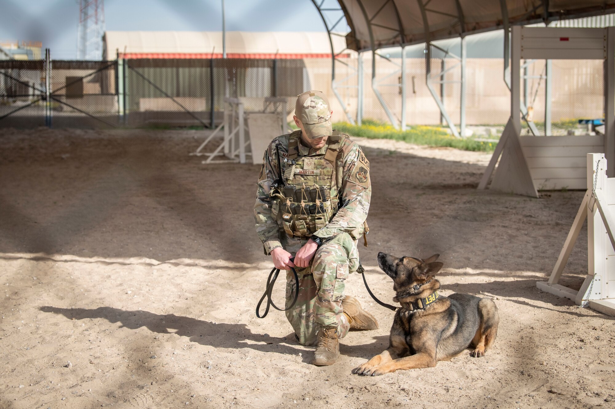 U.S. Air Force Staff Sgt. Jibran Martin, a 386th Expeditionary Security Forces Squadron Military Working Dog handler, looks at MWD Mark during a MWD bite demonstration at Ali Al Salem Air Base, Kuwait, Feb. 16, 2023.