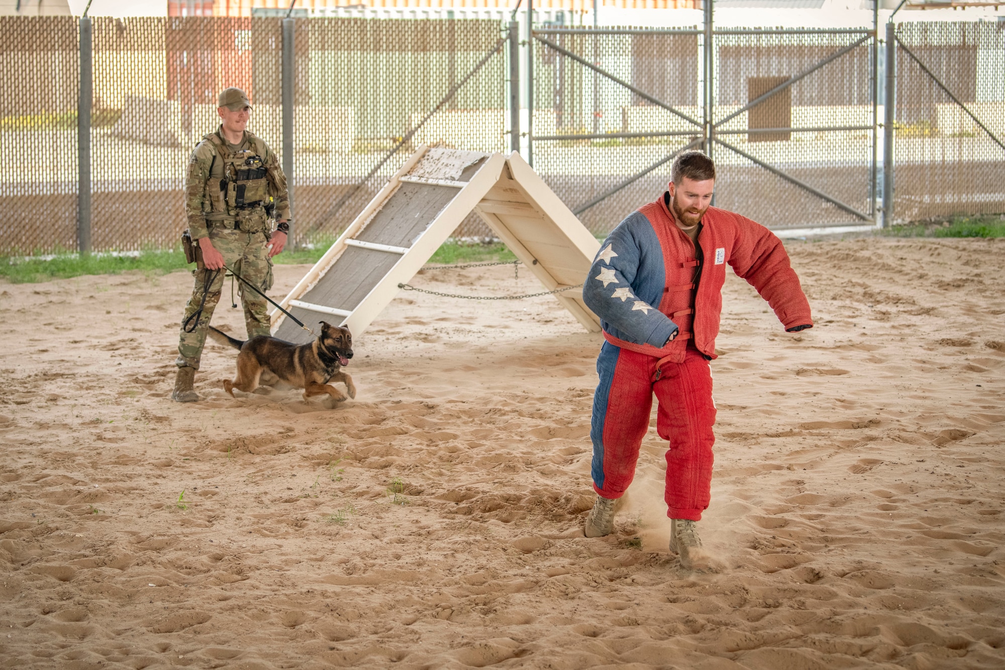 MCpl. Tylar Parsons, a Canadian Armed Forces member, runs from Military Working Dog Azir, assigned to the 386th Expeditionary Security Forces Squadron, during a MWD bite demonstration at Ali Al Salem Air Base, Kuwait, Feb. 16, 2023.
