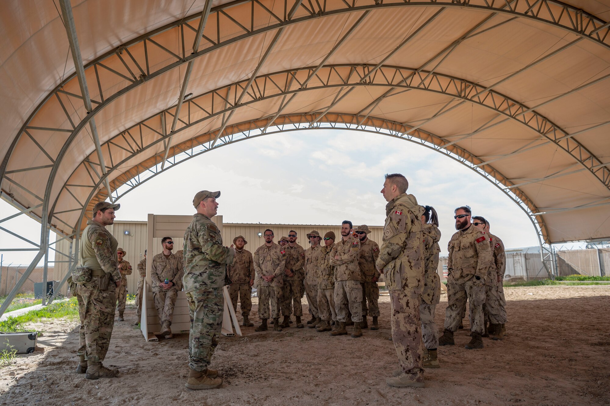 U.S. Air Force Tech. Sgt. Brendan Turner, 386th Expeditionary Security Forces Squadron kennel master, answers Canadian Armed Forces members questions after a Military Working Dog bite demonstration at Ali Al Salem Air Base, Kuwait, Feb. 16, 2023.