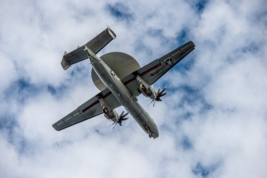 A large aircraft is seen flying from below.