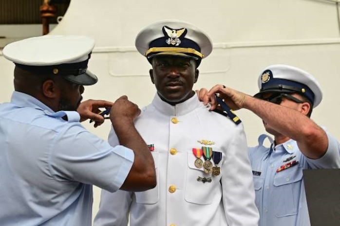 U.S. Coast Guard Ensign Mohammad Diakite, middle, assigned to USCGC Spencer (WMEC 905), is pinned by Chief Petty Officer Andrae Coulter, left, and Petty Officer 1st Class Frederick Garza during his promotion ceremony in Abidjan, Côte d’Ivoire, Feb. 19, 2023.