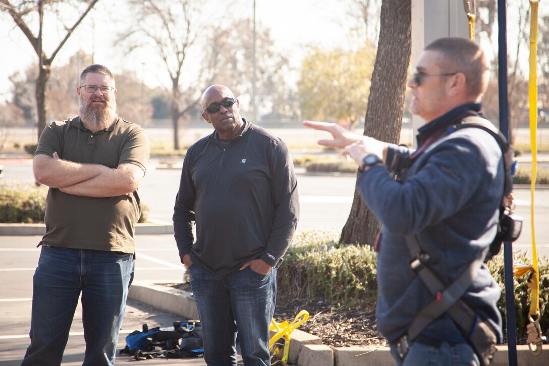 Edward Stewart, a U.S. Army Corps of Engineers senior construction representative, left, and Fred Martin, center, a USACE Construction Representative, listen to Marc Ipsen, a 3M Company fall protection specialist, demonstrate how the proper wear of harnesses can save lives and prevent injuries.