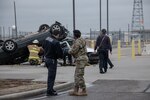 two people watch as firefighters examine crashed cars during training exercise