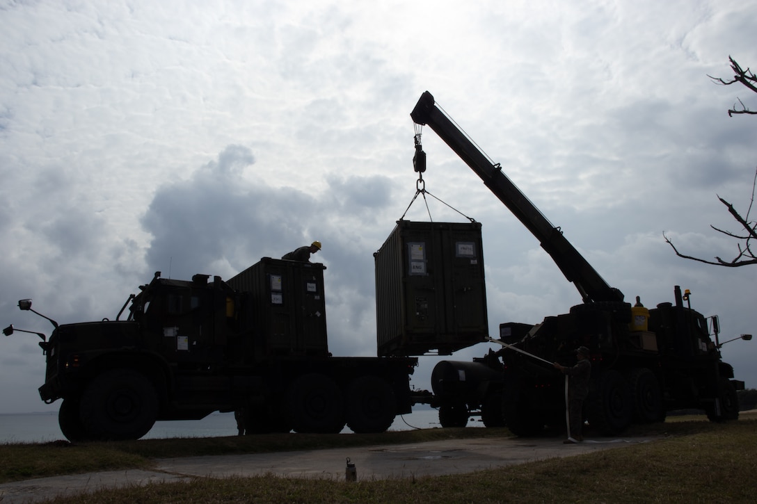 U.S. Marines with Combat Logistics Battalion 31, 31st Marine Expeditionary Unit, lift a quadcon onto a 7-ton vehicle during a combat service support area exercise at Kin Blue, Okinawa, Japan, Feb. 9, 2023. A CSSA provides Marines on the ground with food, water, and fuel to support the mission and sustain an area of operations. The 31st MEU is operating aboard ships of USS America Amphibious Ready Group in the 7th fleet area of operations to enhance interoperability with allies and partners and serve as a ready response force to defend peace and stability in the Indo-Pacific region. (U.S. Marine Corps photo by Cpl. Christopher R. Lape)
