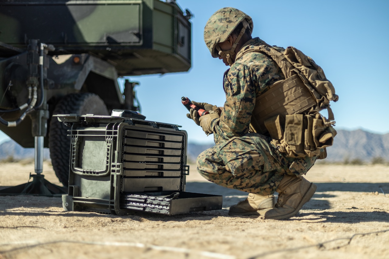 A Marine kneels next to equipment.