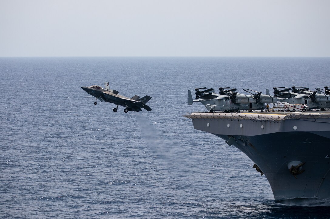 A fighter jet takes off from a ship at sea.