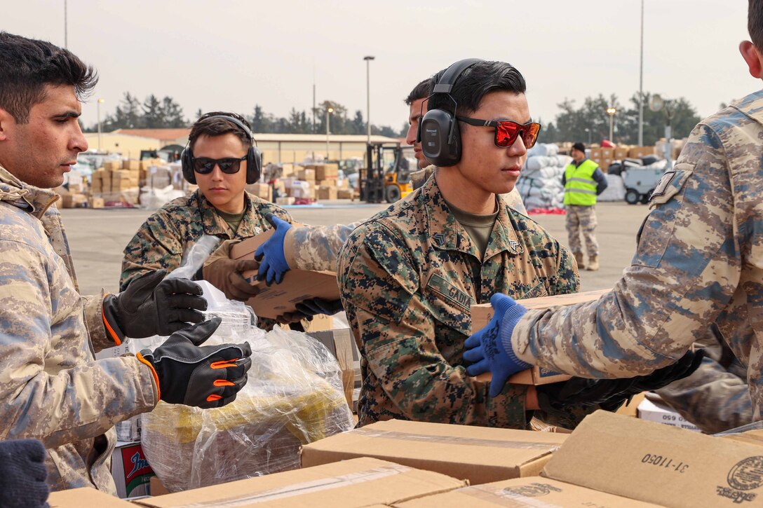 Marines and Turkish soldiers load boxes of supplies.
