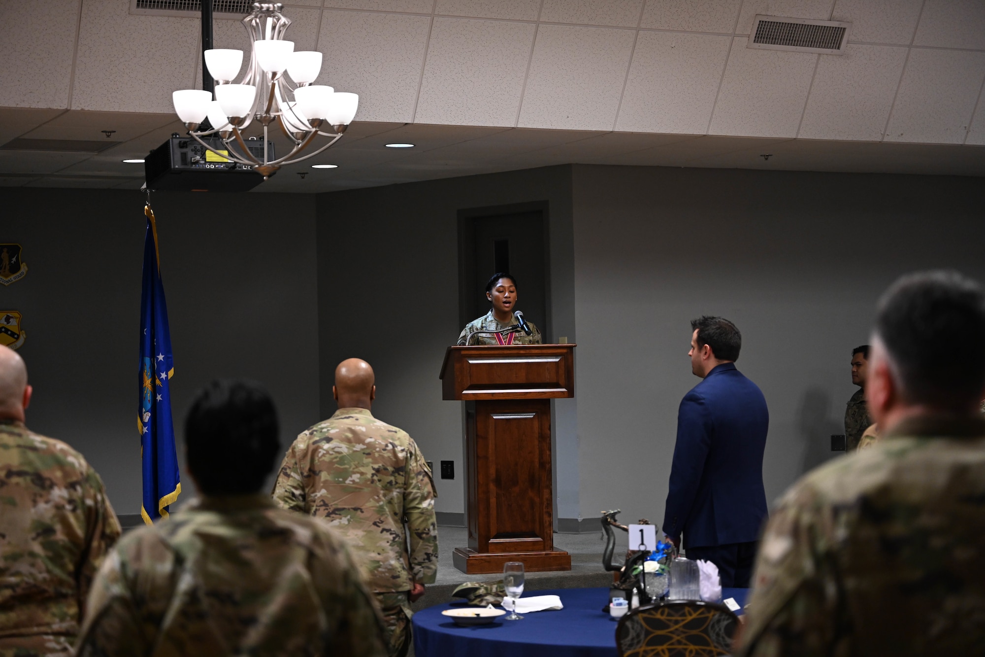 A woman in uniform stands behind a lectern
