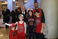 Sgt. Maj. Dennis Koski, rear left, of the 85th U.S. Army Reserve Support Command, pauses for a photo with game spectators after receiving an honor for his service during the Chicago Bulls home game, at the United Center, February 2, 2023, in Chicago.