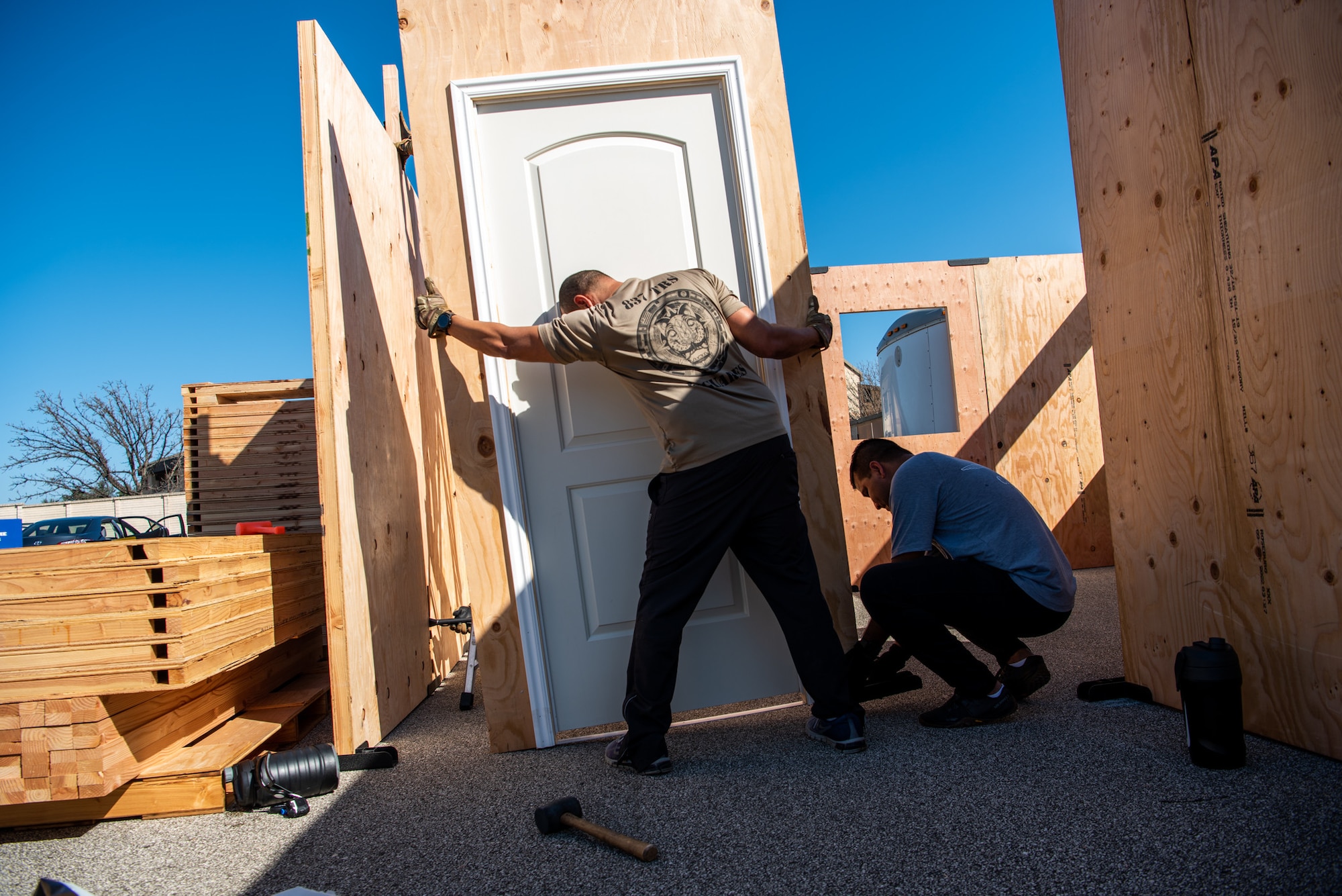 Tech. Sgt. Edwin Nieves, 837th Training Squadron, tilts a door panel, as Intendente Alexander Pacheco, 837th Training Squadron, assists with assembling  the shoot house at the Inter-American Air Forces Academy at Joint Base San Antonio-Lackland, Texas, Jan. 10, 2023. The shoot house is among the newest equipment at the academy that will be used to train international military students from partner nations. The facility consists of modular wood panels that can be easily moved and reconfigured into different layouts, ensuring students remain challenged. (U.S. Air Force photo by Vanessa R. Adame)