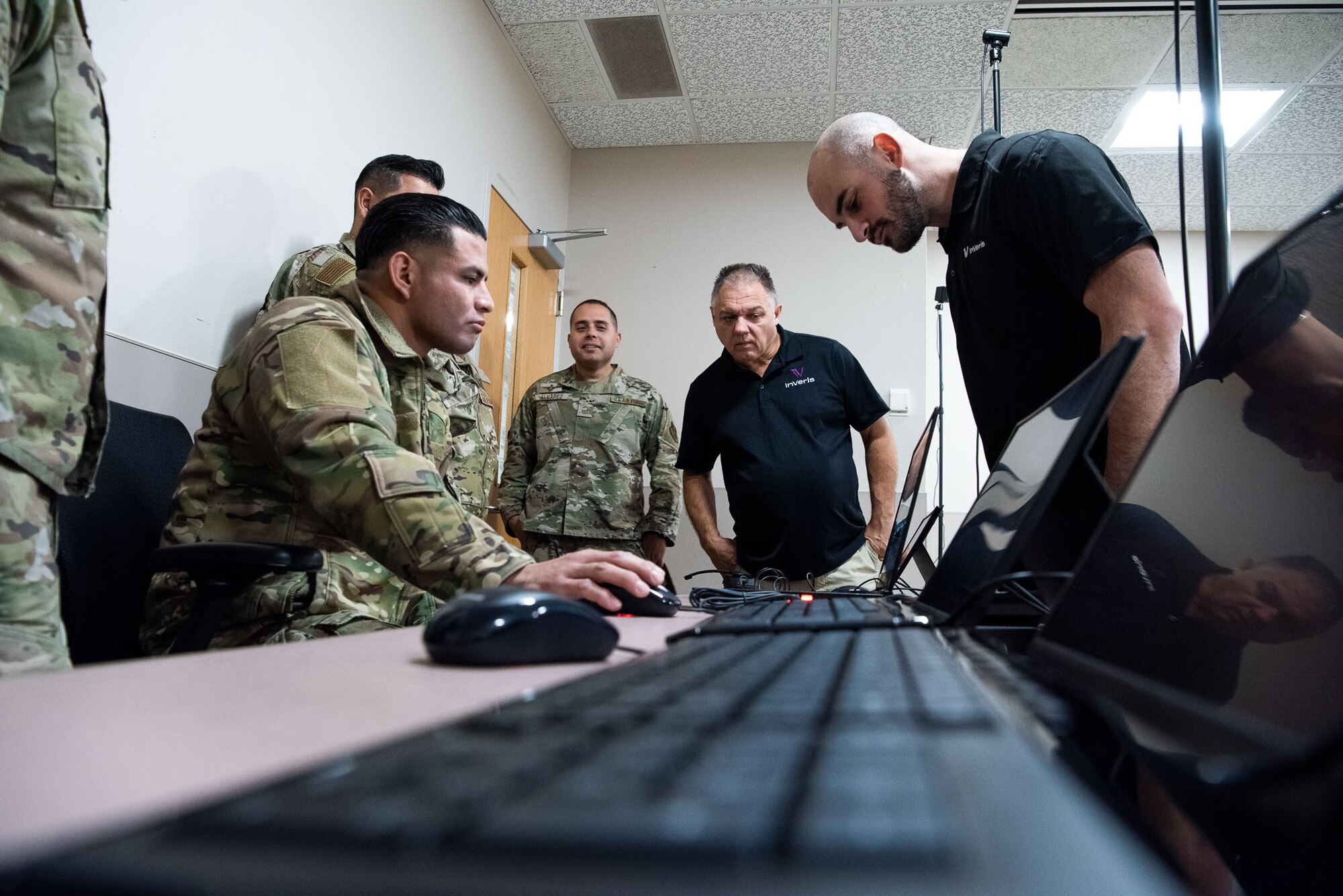 Tech. Sgt. Ernesto Gutierrez, 837th Training Squadron, places his hand on the mouse as he navigates the new SV-R simulator program, as contractors look on at the Inter-American Air Forces Academy at Joint Base San Antonio-Lackland, Texas, Jan. 25, 2023. The simulator will be used to train military and law enforcement students from Latin America, focusing on counter narcotic efforts and combatting transnational criminal organizations. (U.S. Air Force photo by Vanessa R. Adame)