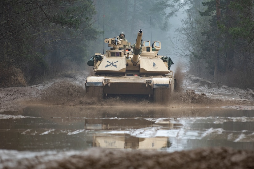 A military tank cruises through muddy water.