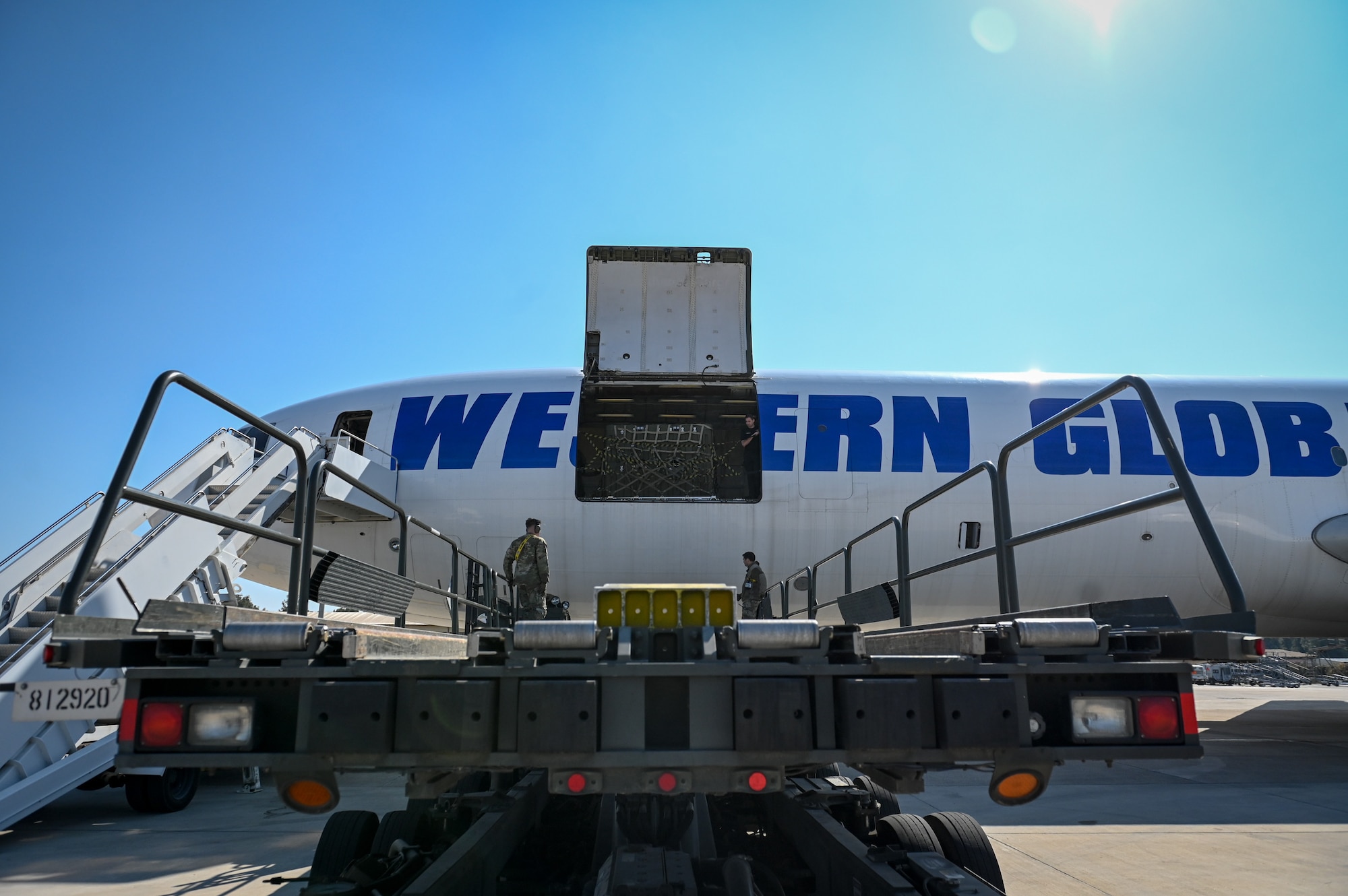 Senior Airman Caleb Hargrove, right, an air transportation specialist assigned to the 728th Air Mobility Squadron, and Senior Airman Devin Shaloy, a passenger services specialist assigned to the 721st Aerial Port Squadron located at Ramstein Air Base, Germany, direct a Tunner 60k Loader at Incirlik Air Base, Türkiye, Feb. 18, 2023.
