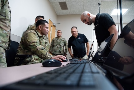 Tech. Sgt. Ernesto Gutierrez, 837th Training Squadron, places his hand on the mouse as he navigates the new SV-R simulator program, as contractors look on at the Inter-American Air Forces Academy at Joint Base San Antonio-Lackland, Texas, Jan. 25, 2023. The simulator will be used to train military and law enforcement students from Latin America, focusing on counter narcotic efforts and combatting transnational criminal organizations. (U.S. Air Force photo by Vanessa R. Adame)