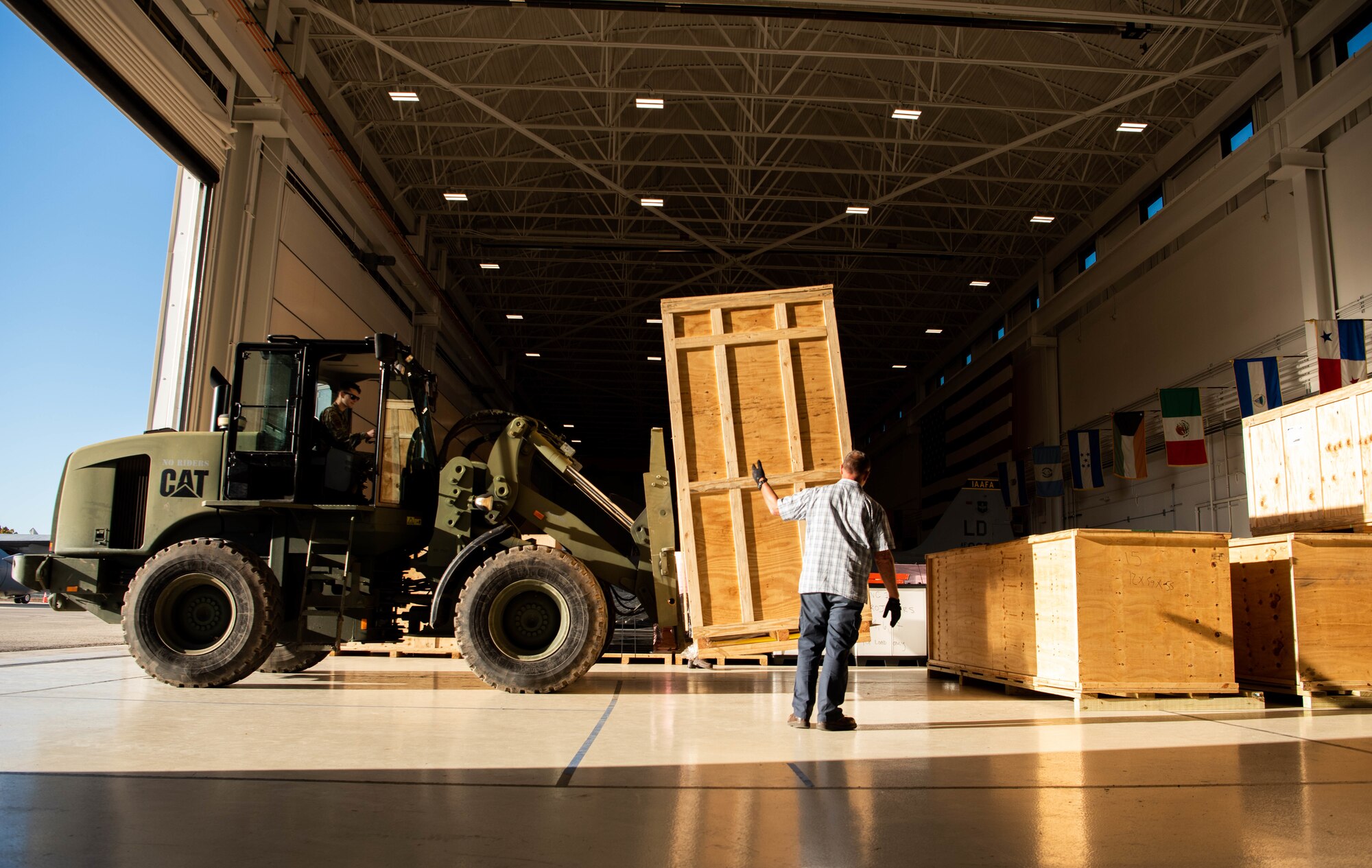 Javier Nagore, 318th Training Squadron Helicopter Maintenance Instructor, signals as the forklift operator delivers a pallet containing parts of the A-29 simulator at Joint Base San Antonio-Lackland, Texas, Nov. 30, 2022. The A-29 Super Tucano will be implemented into the Pilot Instrument Procedures Course curriculum this academic year, with an expansion projected in other courses based on combatant command objectives and partner nation needs. (U.S. Air Force photo by Vanessa R. Adame)