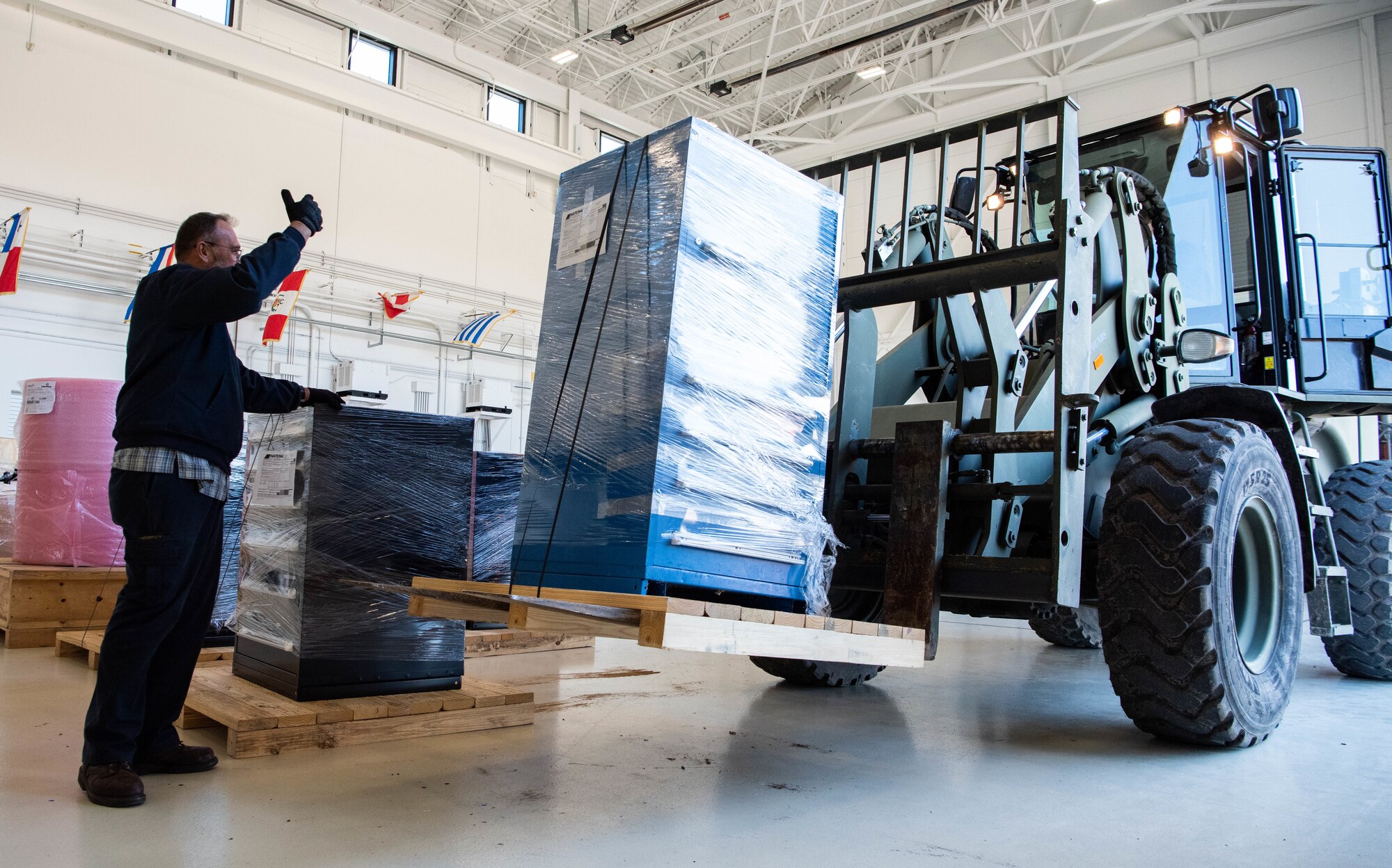 Javier Nagore, 318th Training Squadron Helicopter Maintenance Instructor, motions as the forklift operator delivers packages containing parts of the A-29 simulator at Joint Base San Antonio-Lackland, Texas, Nov. 30, 2022. The A-29 Super Tucano will be implemented into the Pilot Instrument Procedures Course curriculum this academic year, with an expansion projected in other courses based on combatant command objectives and partner nation needs. (U.S. Air Force photo by Vanessa R. Adame)