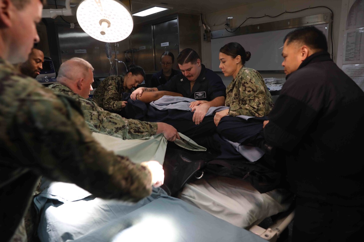 NORFOLK, Va. (Feb. 16, 2023) Wasp-class amphibious assault ship USS Bataan (LHD 5) Medical Department Sailors transfer a simulated casualty into a hospital bed as part of a pier-side trauma training exercise, Feb. 16, 2023. The medical exercise was conducted as part of a Naval Medical Forces Atlantic and U.S. Fleet Forces Command-driven effort to align with and support fleet and joint requirements, and to improve deployment readiness of organic fleet medical departments. During the evolution, the ship’s medical staff participated in several medical scenarios and received real-time feedback in order to build enhanced knowledge and skillsets. (U.S. Navy photo by Mass Communication Specialist 2nd Class Darren Newell)