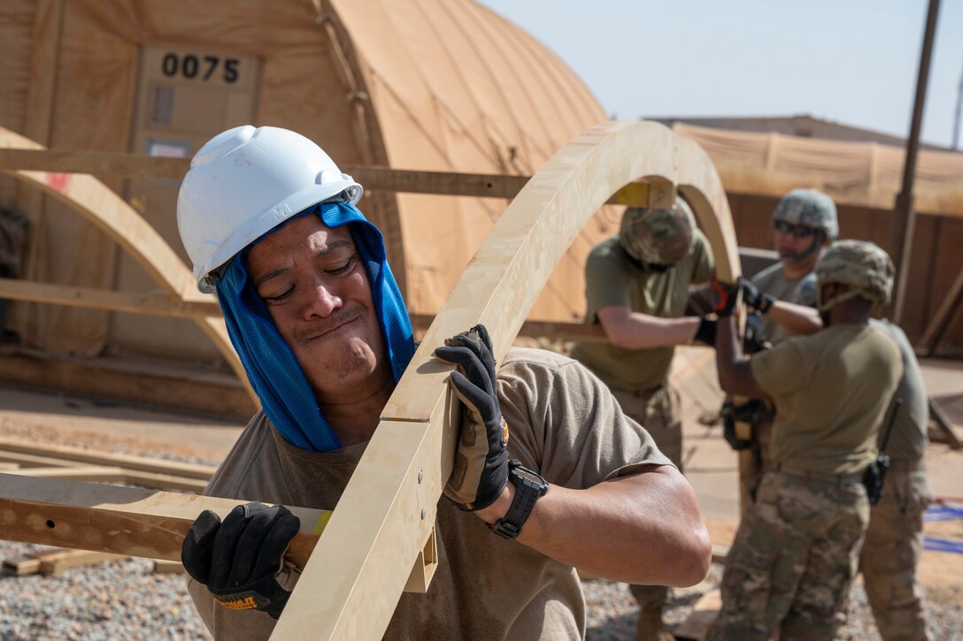 An airman grimaces as he helps put together a large tent.