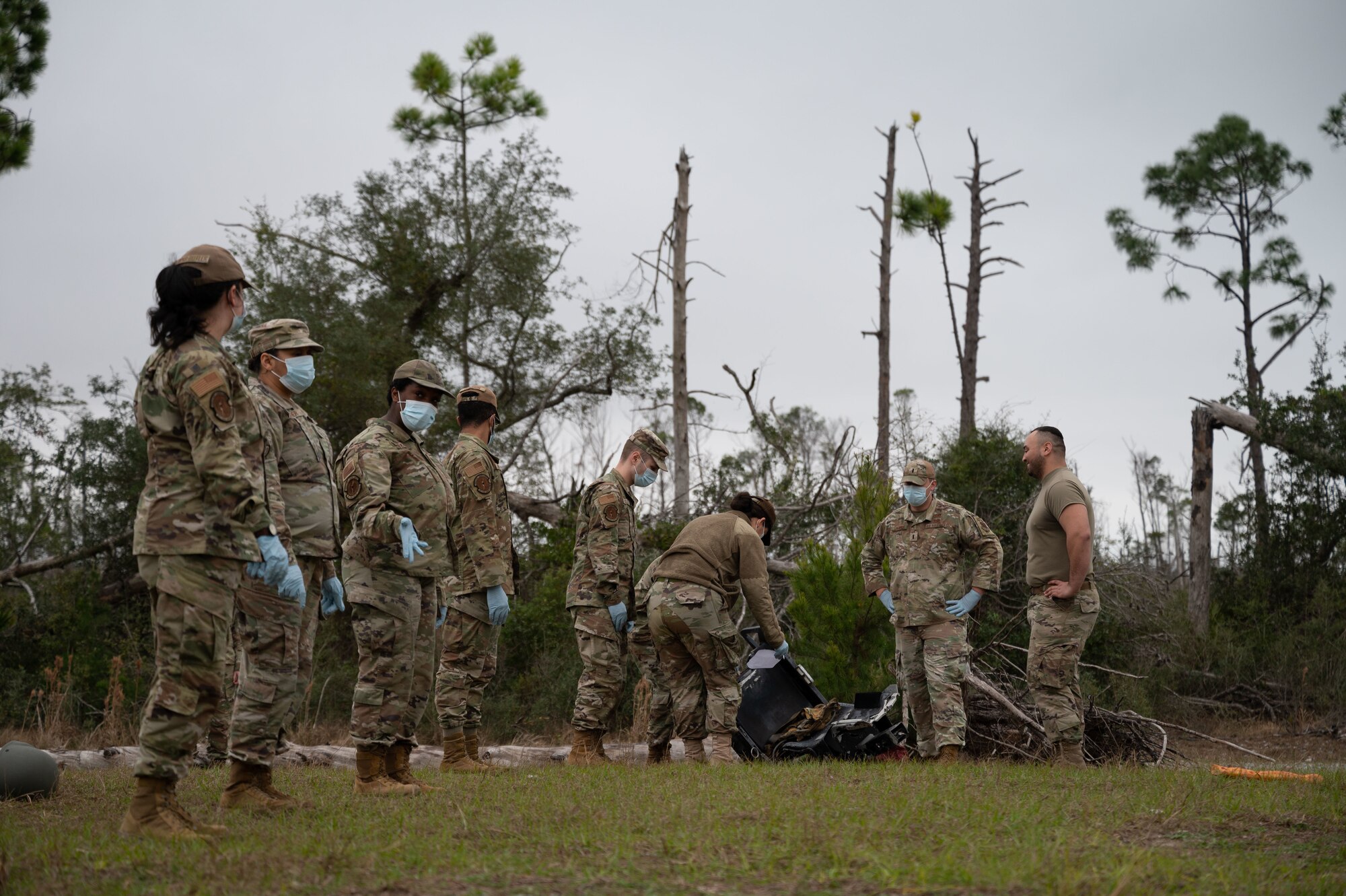 Airmen walk in a field next to a simulates plane crash