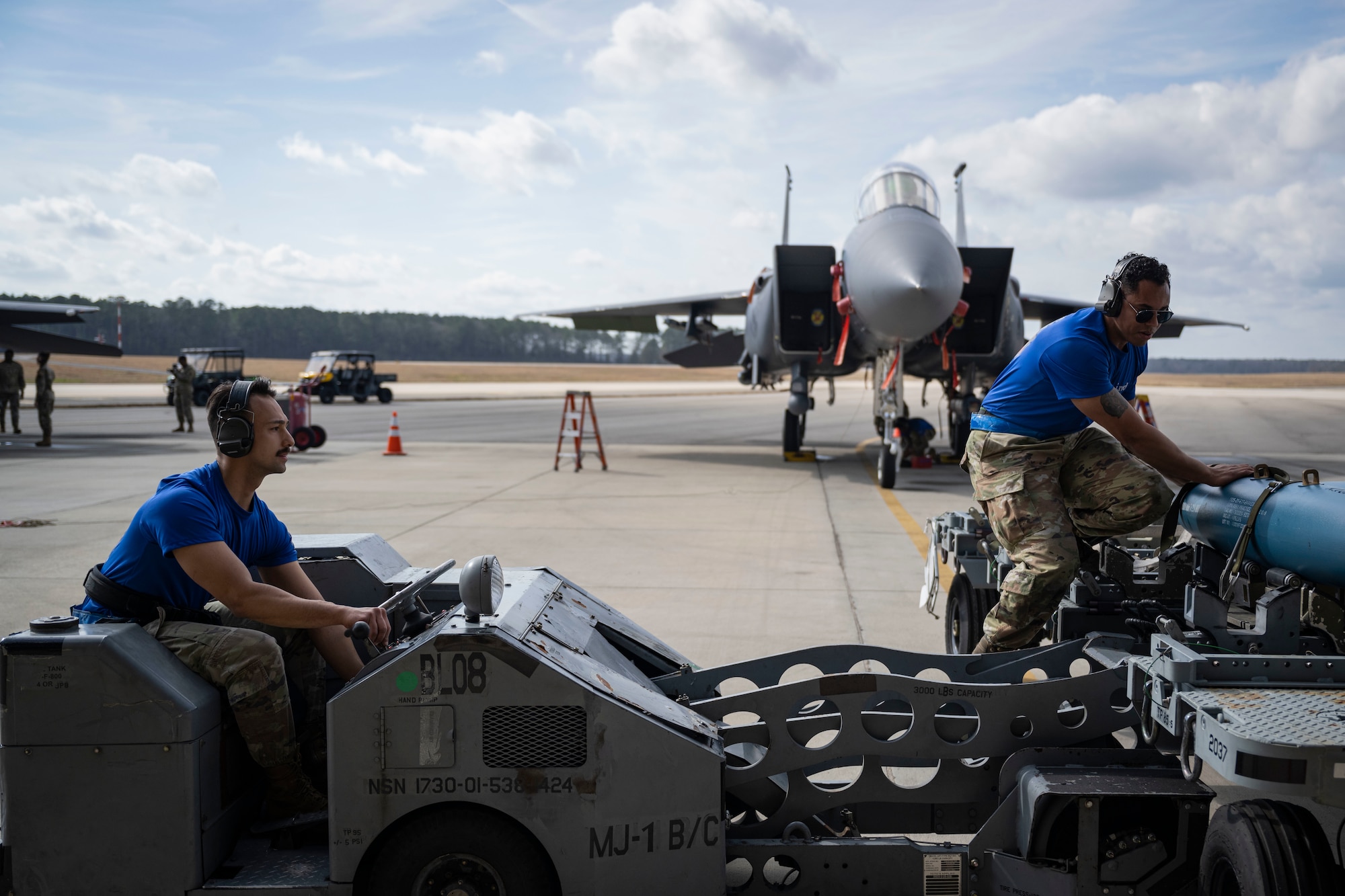 Senior Airman Daniel Gomez, 334th Fighter Generation Squadron three-man load crew member, left, and Staff Sgt. Jovany Rodriguez, 334th FGS weapons load crew team chief, prepare to load a weapon onto an F-15E Strike Eagle during a weapons load crew of the year competition at Seymour Johnson Air Force Base, North Carolina, Feb. 10, 2023. Load crew competitions prepare airmen for fast paced operations they may experience while deployed.