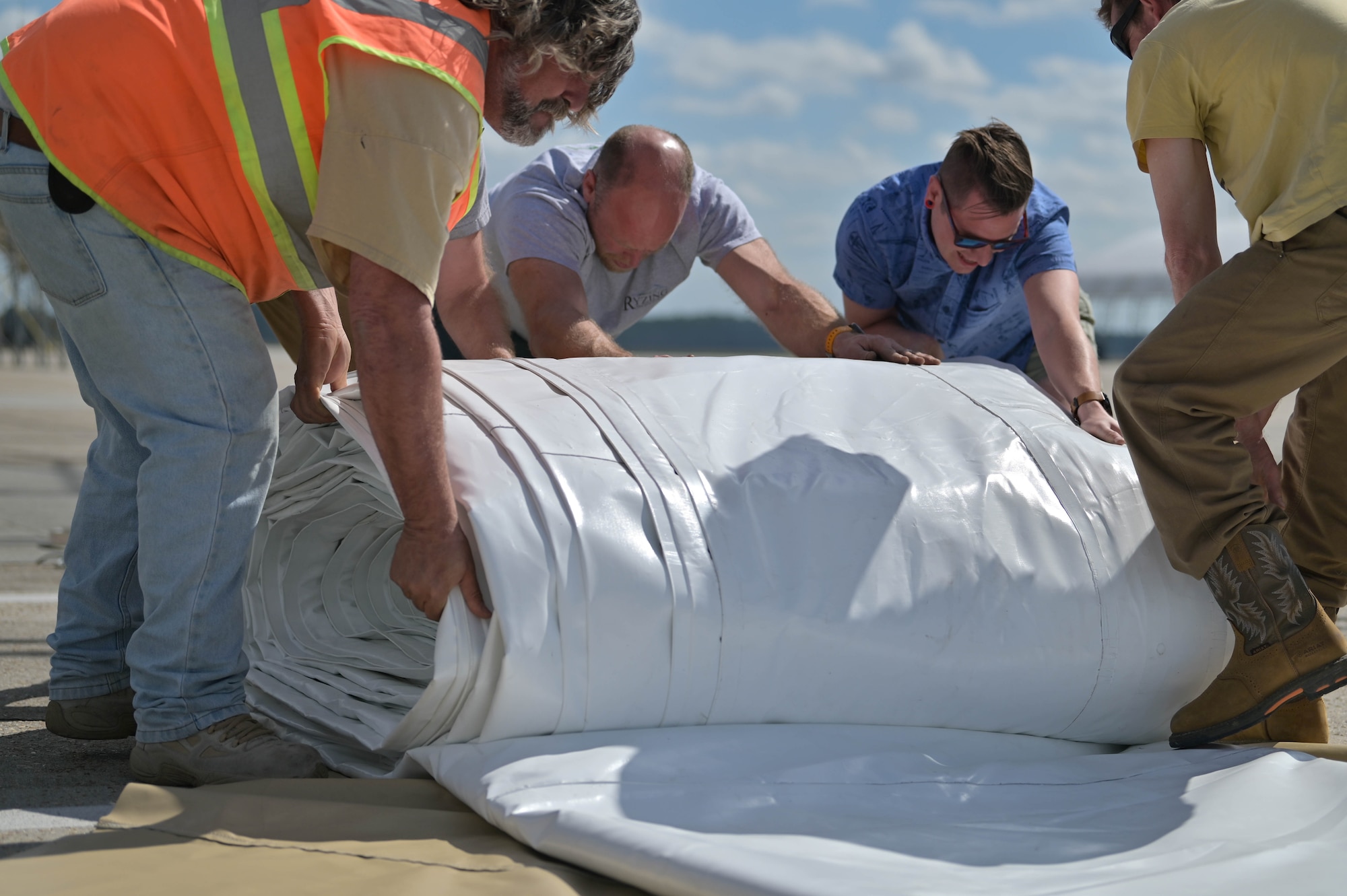 Members from Creative Tent International and Ryzing Technologies roll up fabric for A-10C Thunderbolt II sunshade renovations at Moody Air Force Base, Georgia, Feb. 16, 2023. Upgrades will continue to protect the A-10C Thunderbolt II and allow 74th and 75th Fighter Generation Squadron Airmen to continue doing aircraft maintenance on the jets generated for any kind of mission. (U.S. Air Force photo by Senior Airman Rebeckah Medeiros)