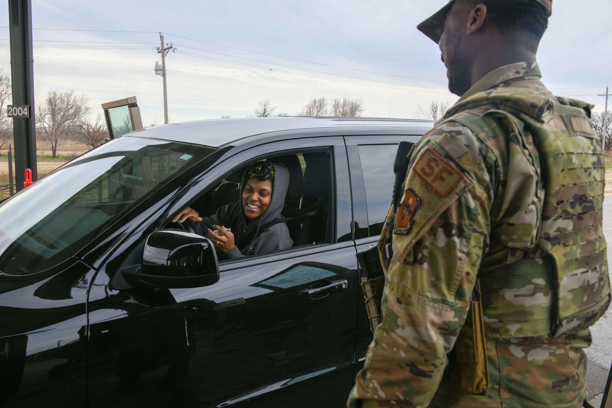 U.S. Air Force Airman 1st Class Michael Mason, 97th Security Forces Squadron patrolman, greets Savon Booker-Hunt at Altus Air Force Base, Oklahoma, Feb. 21, 2023. A patrolman’s many duties include checking identification and vehicle tags for gate entry. (U.S. Air Force photo by Airman 1st Class Miyah Gray)