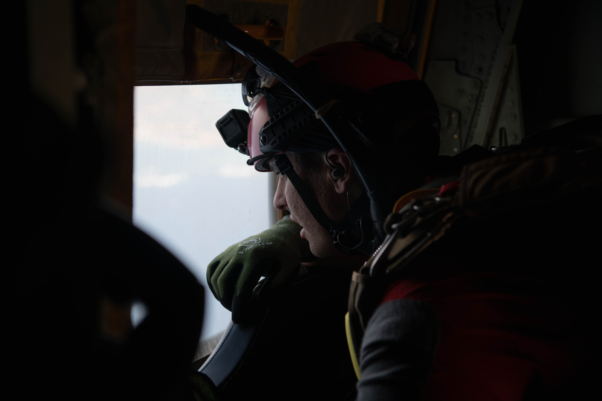 An Airman looks out a window on an aircraft.